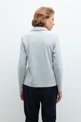Remera de manga larga color gris melange, con cuello polo y escote en V pronunciado.