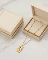Collar de acero con baño de oro, con cadena de eslabones finos y dije rectangular de superficie texturizada con incrustaciones de circonias multicolor.