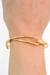 Pulsera rígida dorada con cierre tipo gancho.