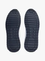 Zapatillas deportivas Tommy Hilfiger de corte bajo, inspiradas en modelos clásicos de running. Presentan un exterior en mezcla de piel blanca con paneles de texturas mixtas, detalles de ventilación en la parte superior y suela de goma con tacos. Incluyen cordones y logo de la marca en el lateral, lengüeta y parte trasera.