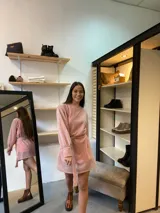 Vestido corto de lurex color salmón con brillo, escote redondo y mangas largas abullonadas. Incluye lazo para marcar la cintura.