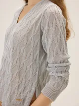 Buzo de tejido en lurex con escote en V, manga larga y silueta relajada, con un brillo sutil y textura tramada.