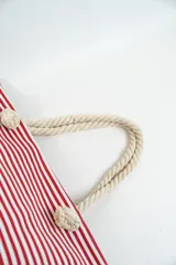 Bolso de tela tipo tote bag con estampado de rayas horizontales azules y blancas, y base de color beige. Tiene asas de cuerda de color beige.