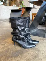 Botas de cuero negro de caña media con diseño fruncido tipo slouchy, punta fina y taco bajo.