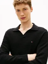 Chomba de manga larga Tommy Hilfiger de color negro, confeccionada en algodón orgánico con tejido de estructura estacional texturizada. Presenta cuello tipo chomba con cartera sin botones y el logo de la marca bordado discretamente en el pecho.