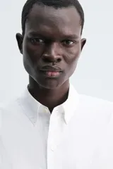 Camisa de corte regular fit confeccionada en popelín de algodón. Presenta cuello abotonado, manga larga con puños ajustables mediante botón y cierre frontal de botonadura completa.