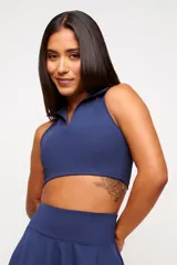 Top deportivo azul marino, estilo polo, sin mangas, con cuello y escote en V. Presenta un corte crop ajustado al cuerpo.