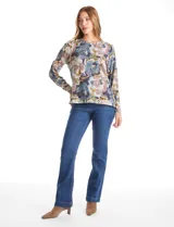 Buzo de hilado fino con cuello redondo y mangas largas. Presenta un estampado floral en tonos grises, azules y ocres, con detalle de botones decorativos en el lateral inferior.