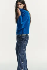 Jersey de punto liso en color azul vibrante, con cuello subido y mangas anchas de diseño acampanado. Presenta acabados en rib en el cuello y los puños.