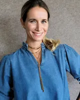 Collar estilo corbatín confeccionado en tiento de cuero color suela, con detalle de cuentas metálicas plateadas distribuidas a lo largo de las tiras.