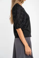 Remera de algodón color rosado con mangas cortas abullonadas de broderie con diseño floral calado. Presenta cuello redondo y costura vertical central en el frente.