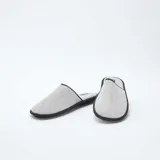 Pantuflas cerradas de tela gris con ribete negro.
