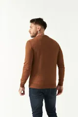 Sweater de punto color negro con escote en V, manga larga y puños acanalados. Presenta un pequeño logo bordado en el pecho.