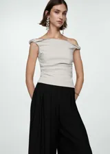 Pantalon wideleg negro de tejido fluido con diseño de tablas frontales y detalle de bordado en el ruedo. Cuenta con cierre delantero de cremallera y botón.