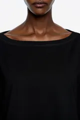 Vestido midi de corte holgado con diseño bimaterial. La parte superior simula una remera de manga larga en color negro, mientras que la falda presenta un estampado animal print en tonos marrones con bajo irregular y fluido.