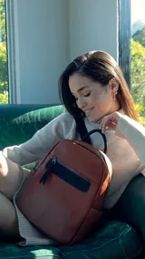 Mochila pequeña de símil cuero color negro, con bolsillo frontal con cierre, asa de mano y correas regulables.