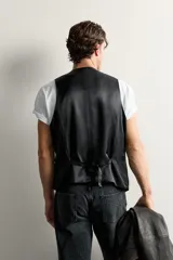 Chaleco regular fit de Zara confeccionado en tejido con lana, color negro, con cuello en V, manga sisa, bolsillos de vivo en la cintura, trabilla ajustable en la espalda y cierre frontal de botonadura.