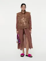 Chaleco denim rosa con efecto metalizado plateado, sin mangas y con cierre de botones.