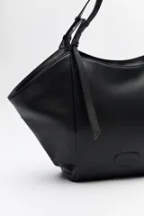 Bolso negro tipo tote de cuero sintético con acabado soft touch, asas largas regulables y diseño minimalista.