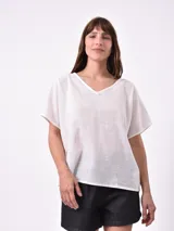 Blusa blanca de lino con escote en V y mangas cortas amplias.