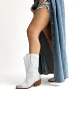 Bota texana de caña media confeccionada en cuero gamuzado blanco, con diseño perforado en la caña, puntera redondeada con efecto desgastado y suela de madera.