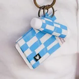 Billetera elástica de diseño compacto con estampado de bloques en tonos azul y blanco. Cuenta con una argolla metálica lateral para enganchar llaves y una pequeña etiqueta con el logo de la marca.