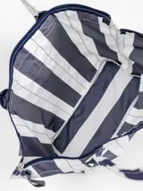 Bolso tipo tote grande, resistente al agua, con diseño de rayas verticales rojas y blancas. Cuenta con asas largas de hombro, cierre superior y parche de cuero con logo grabado. Incluye neceser transparente a juego con base y detalles a rayas.