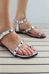 Sandalias plateadas de cuero italiano con base ultraliviana y detalle de piedras negras y transparentes en las tiras.