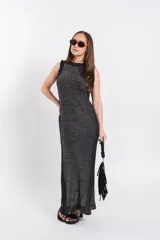 Vestido largo de tejido de punto con brillo, color negro con sutiles hilos metalizados, sin mangas, con cuello alto y aberturas laterales.