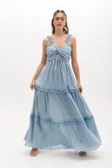 Vestido largo blanco de gasa de algodón con textura liviana. Tiene escote en V con nudo central, breteles con voladitos y falda con frunces.