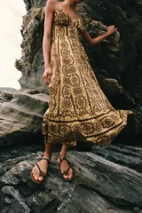 Vestido midi de broderie en tonos mostaza y marrón, con escote en V, tirantes finos ajustables, abertura cut-out en la cintura y espalda con nido de abeja elástico.