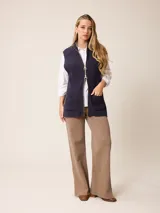 Chaleco de tejido de punto en color gris, con cierre frontal completo, cuello alto y dos bolsillos delanteros tipo parche.