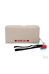 Billetera rectangular de cuero sintético color beige con cierre perimetral. Presenta un parche frontal blanco con la inscripción 'MON AMOUR' y el logo de la marca en color rojo. Incluye una correa de muñeca negra con rayas blancas y un dije colgante en forma de labios.