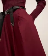 Pollera evasé midi color borgoña, confeccionada en tricolina de algodón sostenible, con tiro alto, pliegues delanteros y cierre trasero por cremallera.