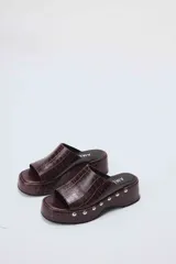 Sueco de cuero color marrón con plataforma y detalle de tachas plateadas.