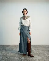 Falda larga cruzada de lana con apariencia de denim, con diseño envolvente, abertura frontal y lazo lateral para ajuste. Presenta pespuntes a contratono y terminaciones desflecadas.