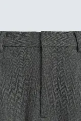Pantalón de traje relaxed fit en color gris oscuro con diseño de espiga. Cuenta con bolsillos frontales, bolsillos traseros de vivo y cierre frontal con cremallera y botón.