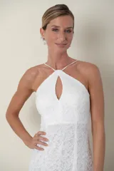 Vestido largo de encaje blanco, con breteles finos cruzados en la espalda y escote halter con abertura en forma de gota.