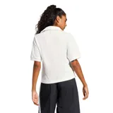 Remera Adidas de corte polo con cuello abierto, manga corta y logo bordado en color verde sobre fondo blanco.