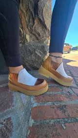 Zapatos de cuero estilo botineta baja en combinación de tonos marrones y beige, con suela chunky de plataforma plana y diseño texturizado en el talón.