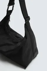 Bolso de hombro tipo hobo fabricado en tejido técnico de nylon. Cuenta con un compartimento principal con cierre de cremallera, un bolsillo interior con cierre y un asa ajustable con detalle de mosquetón.