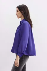 Camisa fluida de manga larga, color negro, con cuello camisero, puño con botón y detalle de frunces.