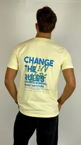 Remera de algodón color amarillo suave, con cuello redondo y mangas cortas. Presenta una estampa frontal pequeña en el pecho con el texto 'CHANGE THE RULES' en color azul.