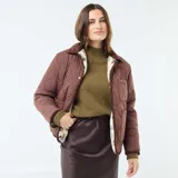 Chaqueta de sherpa color crema con estampado floral en tonos marrones, amarillos y verdes. Tiene cuello camisero y ribete de pana marrón.