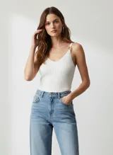 Top de punto acanalado color blanco, con escote en V y tirantes finos ajustables con hebillas metálicas doradas.