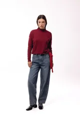 Sweater de punto color bordó con textura de relieve tipo pompones, cuello alto y mangas largas. Presenta un diseño con un lazo lateral que permite ajustar la prenda en la cintura.