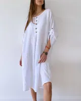 Vestido blanco de lino, corte holgado, con cuello redondo, mangas 3/4 con botones y cierre frontal parcial con botones de madera.