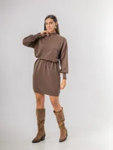 Vestido tipo polerón de tejido de punto color borgoña, con cuello alto, mangas largas con puños ajustados y corte recto. Incluye un cinturón del mismo material con una hebilla decorativa de flor con cristales.