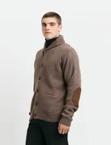 Cardigan de punto color marrón con cuello esmoquin, cierre frontal con botones y presilla superior. Presenta mangas largas con coderas en contraste y bolsillos frontales de ribete.