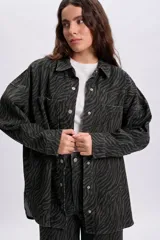 Sobrecamisa de denim con estampa de cebra en color verde militar, de corte oversize, cuello camisero, bolsillos frontales con solapa y cierre de botones metálicos.